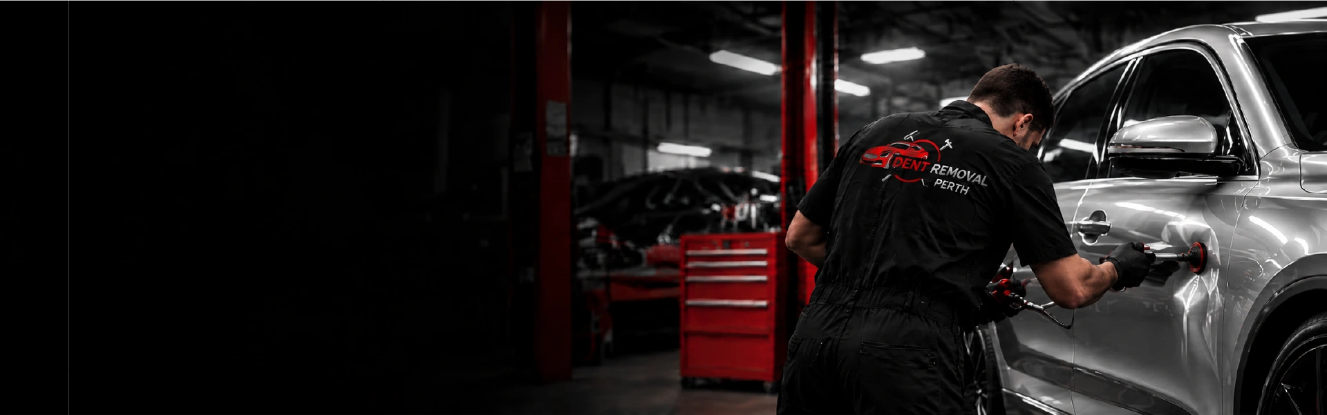 Technician repairing a dent on a black car